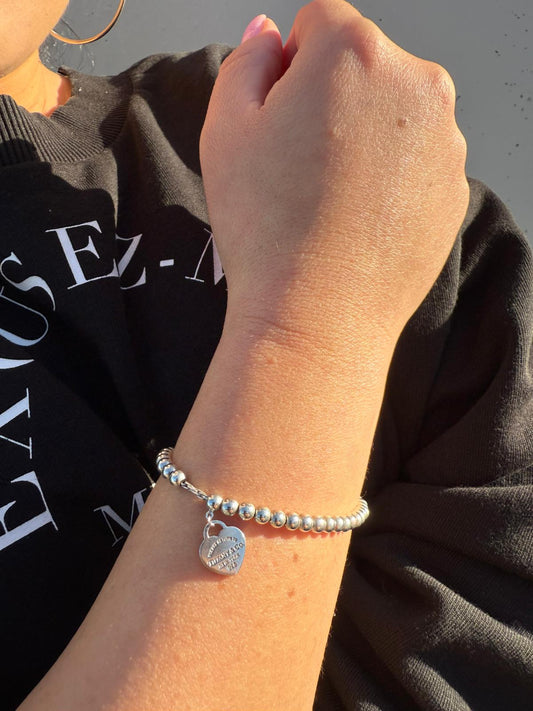 Ragazza che indossa un Bracciale Heart Tag Tiffany&Co. della collezione Return To Tiffany in argento 925 con ciondolo cuore. Originale, usata, di lusso, in ottime condizioni.