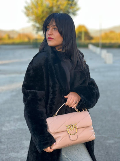 Ragazza che indossa una Borsa Pinko in pelle trapuntata rosa cipria con parti metalliche dorate; munita di un manico e una tracolla in pelle leggermente regolabile e amovibile. Completa di dustbag e cartellino. Originale, usata, di lusso, in ottime condizioni.