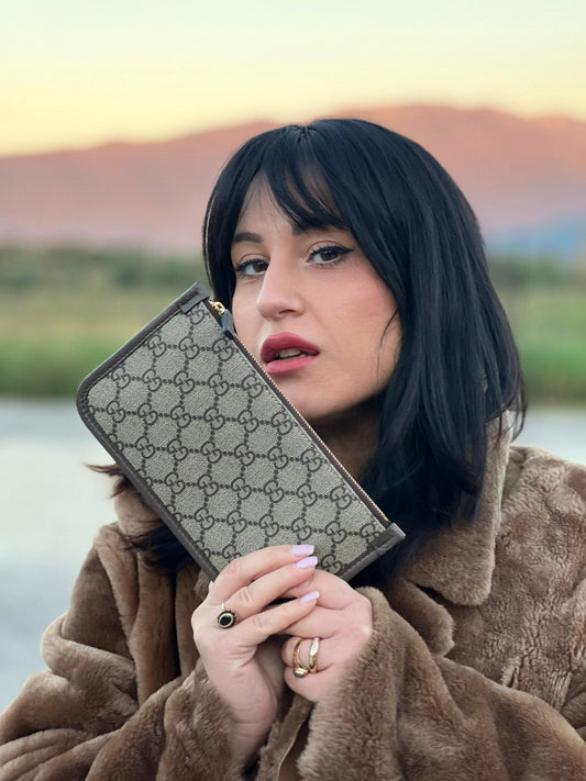 Ragazza che indossa un Accessorio Pochette Gucci per borse in canvas beige GG con inserti metallici dorati e dettagli in pelle martellata marrone. Completa di dustbag. Originale, usata, di lusso, in ottime condizioni