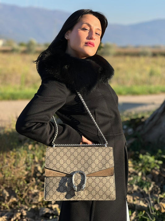 Ragazza che indossa una Borsa Gucci in canvas GG beige con finiture in pelle scamosciata tono su tono e parti metalliche argentate; con l'conica chiusura con teste di tigri decorative, munita di una tracolla in catena scorrevole, ma non amovibile. Indossabile a tracolla oppure a spalla. Originale, usata