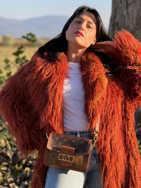 Ragazza che indossa una Borsa Dauphine Mini Louis Vuitton in tela monogram, e monogram reverse bicolore con finiture in pelle cognac e parti metalliche dorate, munita di una tracolla in pelle allungabile e un manico in catena, amovibili. Originale, usata, di lusso, in ottime condizioni