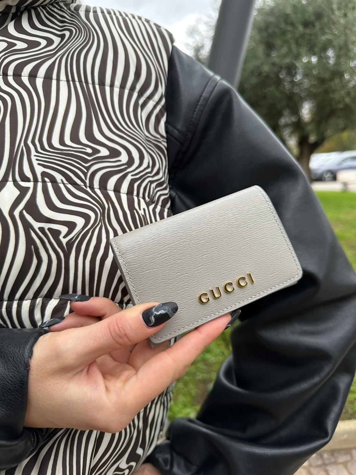 Rgazza che indossa un Portafoglio Gucci in pelle Grigia con parti metalliche dorate. Completo di scatola e dustbag. Originale, usato, di lusso in condizioni eccellenti.