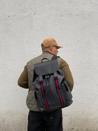 Ragazzo che indossa un Zaino Gucci in canvas grigio GG con finiture in pelle neri e parti metalliche argentate. Iconica striscia Web in blu/rosso sul front, munito di un manico singolo, Bretelle imbottite regolabili e patta con moschettoni a scatto. Completo di dustbag. Originale, usato, di lusso, in condizioni eccellenti.