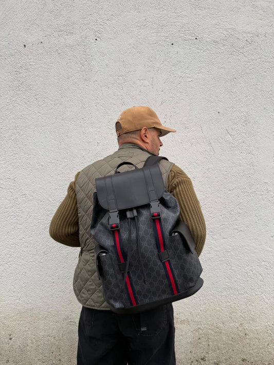Ragazzo che indossa un Zaino Gucci in canvas grigio GG con finiture in pelle neri e parti metalliche argentate. Iconica striscia Web in blu/rosso sul front, munito di un manico singolo, Bretelle imbottite regolabili e patta con moschettoni a scatto. Completo di dustbag. Originale, usato, di lusso, in condizioni eccellenti.