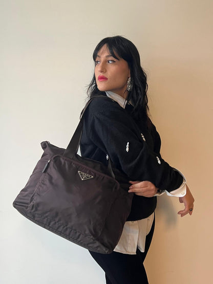 indossata Borsa Prada in nylon marrone scuro con parti metalliche argentate , munita di doppi manici in tessuto, indossabile a spalla.