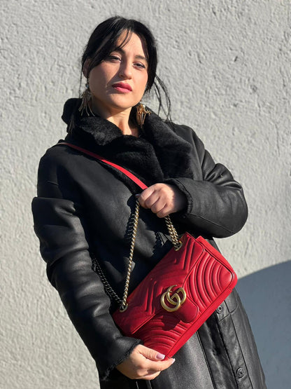 Ragazza che indossa una Borsa Gucci Marmont in pelle matelassé rossa con tracolla scorrevole in catena e spallaccio in pelle, rifinita con parti metalliche dorate. Completa di dustbag. Originale, usato, di lusso, in ottime condizioni.