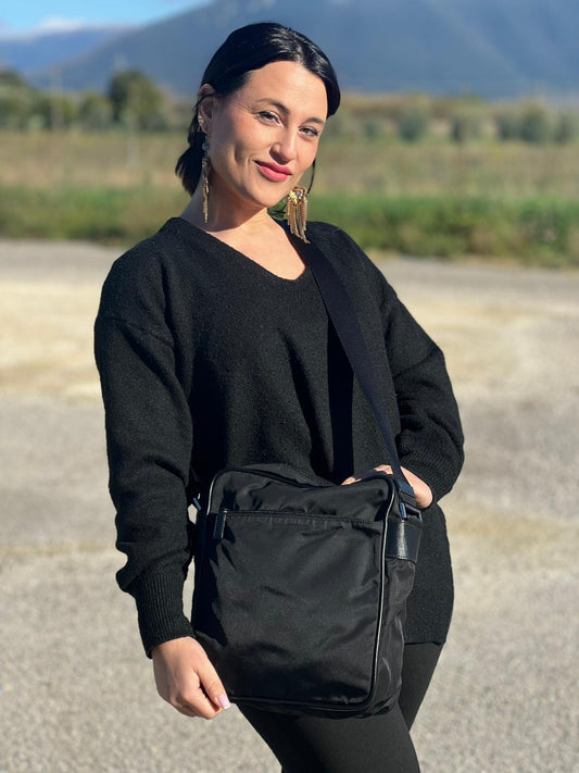 Ragazza che indossa un Front di una Borsa Prada in nylon nero con finiture in pelle tono su tono e parti metalliche argentate; munita di una tracolla in tessuto regolabile. Originale, usata, di lusso, in ottime condizioni