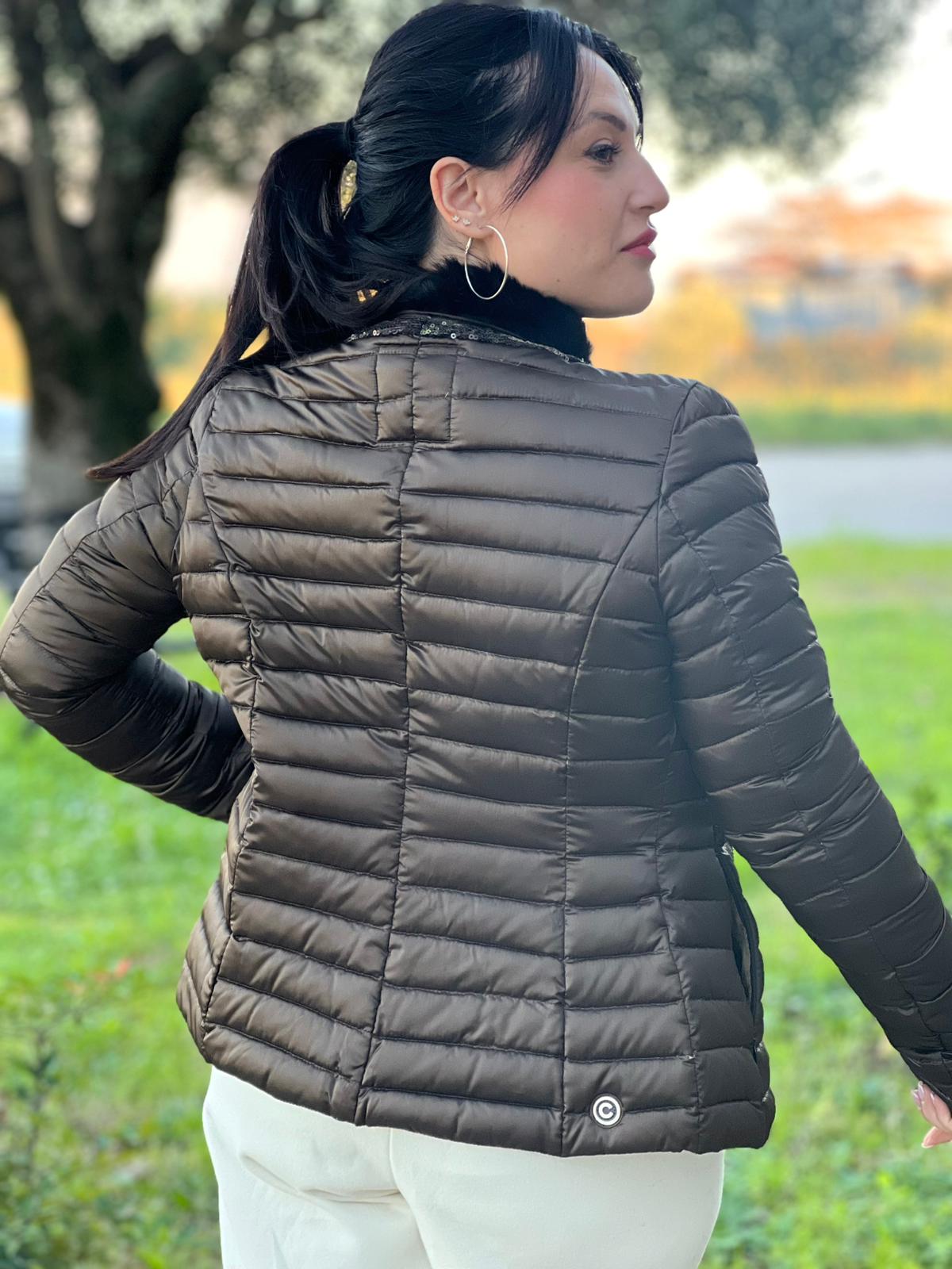 Ragazza che indossa un Piumino Colmar in100% poliestere trapuntata in tonalità bronzo, impreziosita da colletto in pelliccia sintetica e bordature con paillettes lungo la zip frontale. Originale, usato, di lusso, in ottime condizioni.