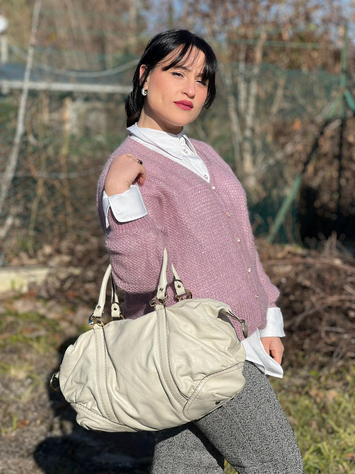 Ragazza che indossa un Bauletto Gucci in pelle bianco avorio parti metalliche dorate, munita di due manici stondati. Indossabile a mano. Originale, usato, di lusso, in ottime condizioni.