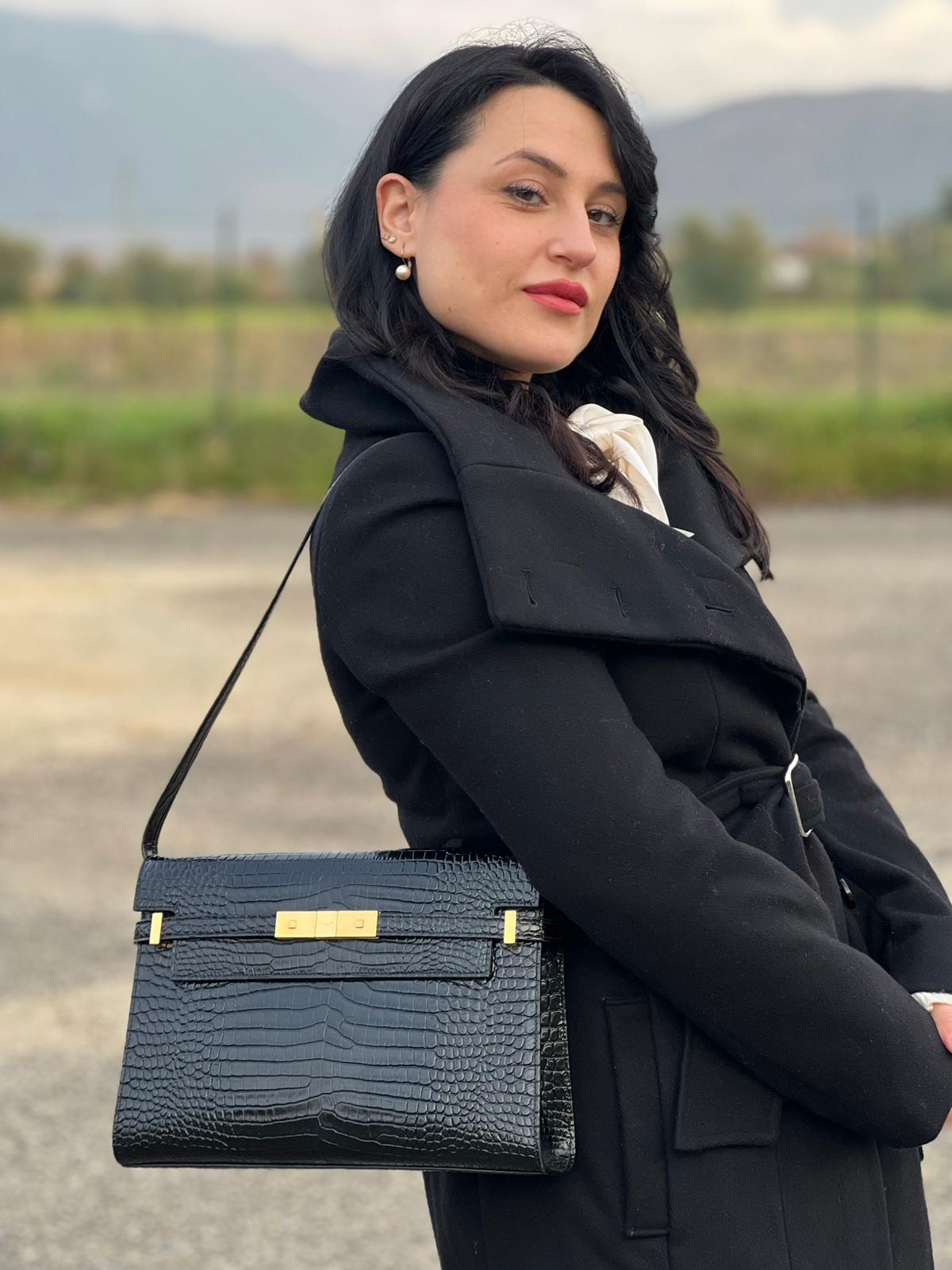 Ragazza che indossa una Borsa Saint Laurent in pelle nera in trama cocco con parti metalliche dorate. Munita di una tracolla regolabile con fibbia. Originale, usata, di lusso, in ottime condizioni.