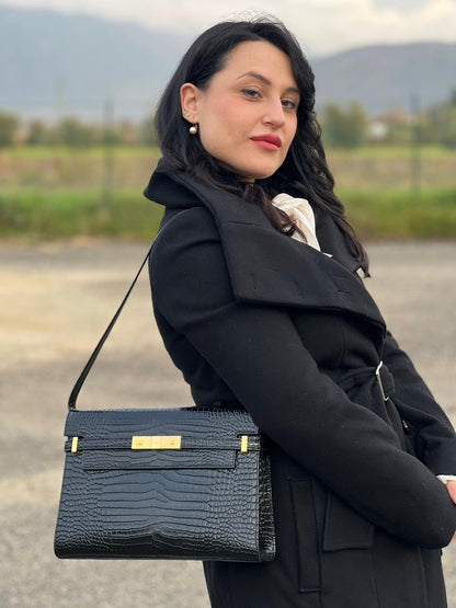 Ragazza che indossa una Borsa Saint Laurent in pelle nera in trama cocco con parti metalliche dorate. Munita di una tracolla regolabile con fibbia. Originale, usata, di lusso, in ottime condizioni.