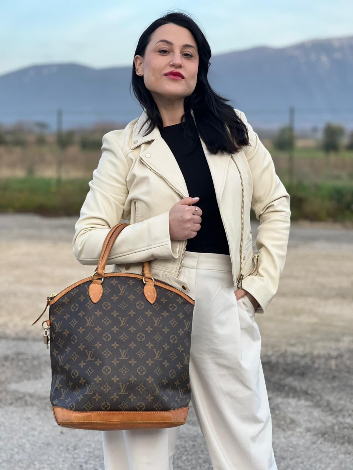 Ragazza che indossa una Borsa Louis Vuitton in canvas marrone monogram con finiture in vacchetta naturale e parti metalliche dorate. Munita di doppi manici stondati. Completa di dustbag, lucchetto e chiavi. Originale, usata, di lusso, in ottime condizioni.