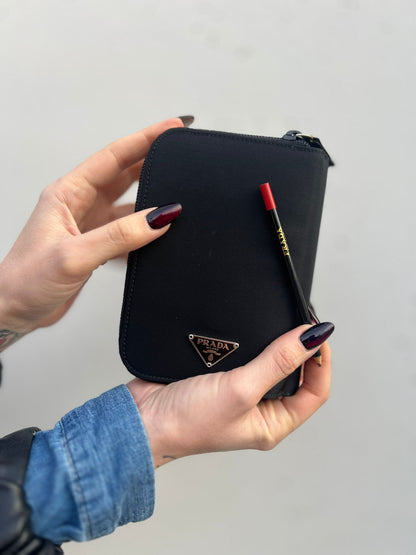Ragazza che indossa unPorta agenda Prada in tessuto nylon nero e finiture in pelle, con parti metalliche argentate; organizzato con portacarte, portapenne e pratico raccoglitore ad anelli per i fogli. Originale, usato, di lusso, in condizioni eccellenti.