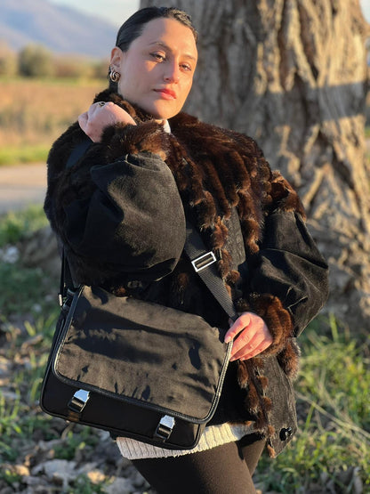 Rgazza che indossa una Borsa Prada in nylon nero con finiture in pelle tono su tono e parti metalliche argentate; munita di una tracolla regolabile in tessuto. Originale, usata, di lusso, in ottime condizioni.