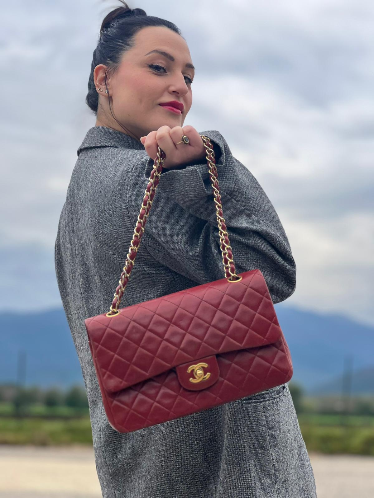 Ragazza che indossa una Borsa Chanel in pelle color terra di siena bruciata matelassè con parti metalliche dorate; munita di una tracolla scorrevole in catena e pelle. Indossabile a spalla e a tracolla. Completa di scatola e Dustbag. Originale, usata, di lusso, in ottime condizioni.