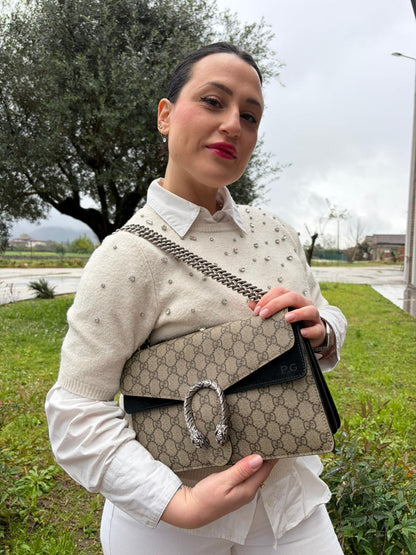 Ragazza che indossa una Borsa Gucci in canvas beige monogram GG, finiture in pelle scamosciata nera e parti metalliche argentate; munita di una tracolla in catena scorrevole. Indossabile a spalla oppure a tracolla. Originale, usata, di lusso, in ottime condizioni.