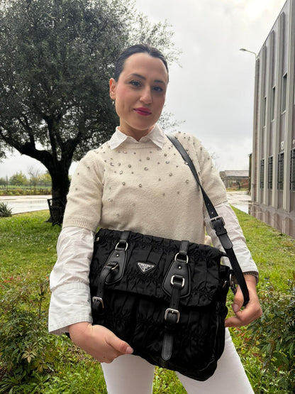 Ragazza che indossa una Borsa Prada in tessuto nylon goffrato nero con parti metalliche argentate e inserti in pelle tono su tono, munita di una tracolla regolabile e amovibile. Completa di dustbag. Originale, usata, di lusso, in ottime condizioni.