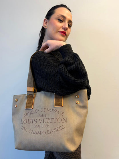 Ragazza che indossa una Borsa Louis Vuitton Limited Edition in tela beige con dettagli in pelle scamosciata marrone e in vacchetta naturale, parti metalliche dorate; munita di doppi manici in tessuto, indossabile a spalla. Completa di dustbag. Originale, usata, di lusso, in ottime condizioni