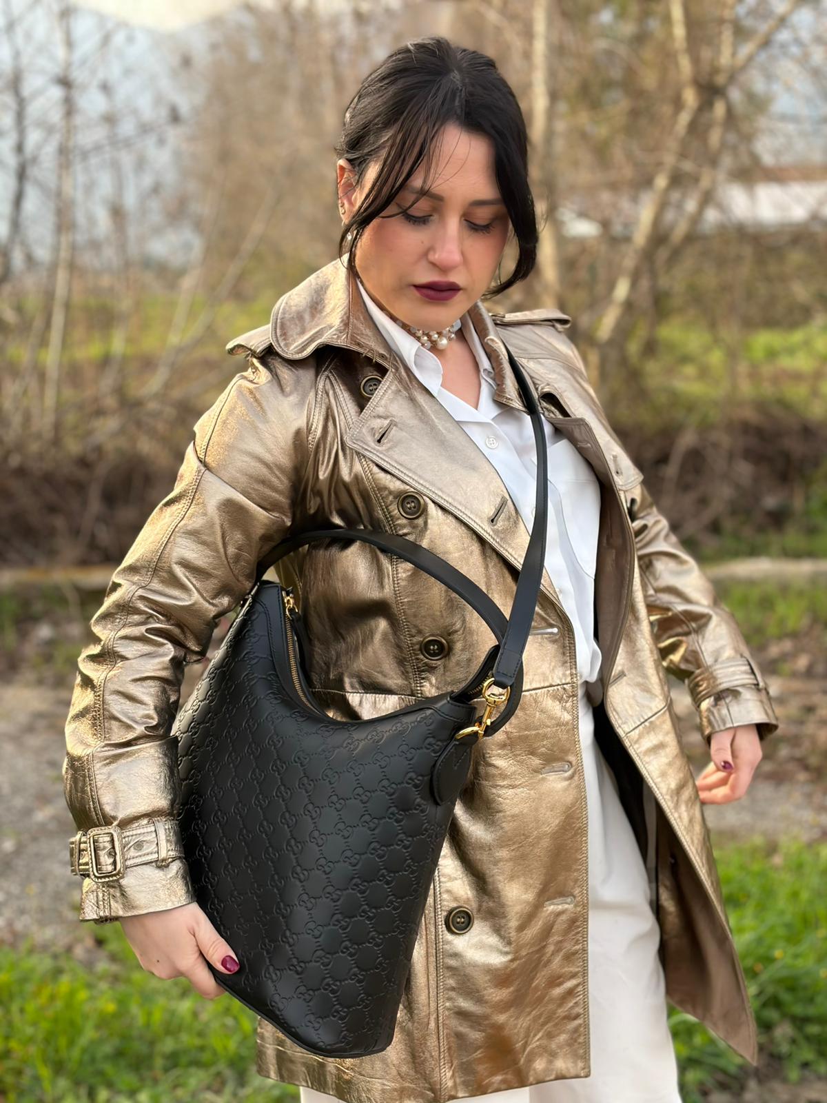 Ragazza che indossa Borsa Gucci in pelle nera GG con hardware dorato. Originale, usata, di lusso, in condizioni eccellenti.