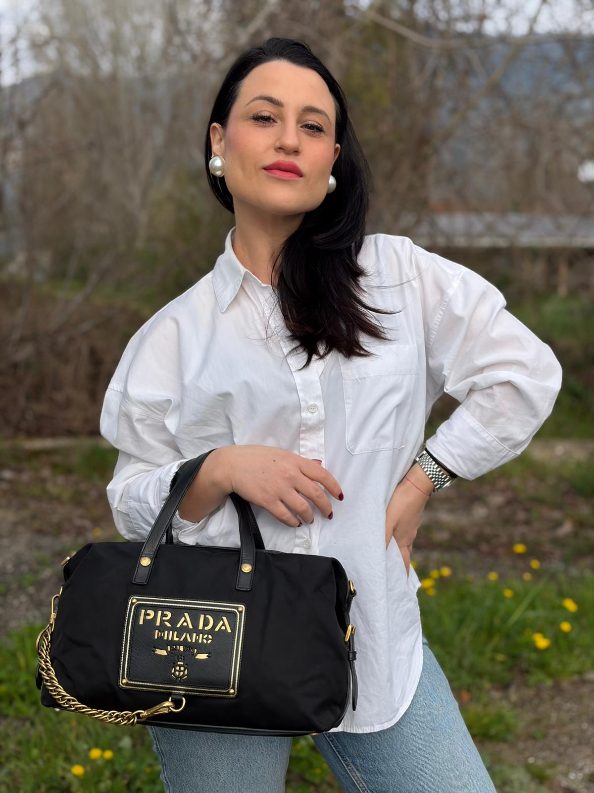 Ragazza che indossa un bauletto Prada in tessuto vela e dettagli dorati, indossabile a mano, usato, originale, second hand, in ottime condizioni.