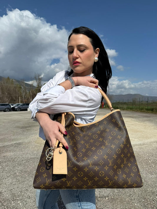Ragazza che indossa una borsa Again Louis Vuitton, rivisitazione dell'iconica Artsy, in canvas monogrammato e dettagli in vacchetta naturale, usata, originale, second hand, in condizioni eccellenti.