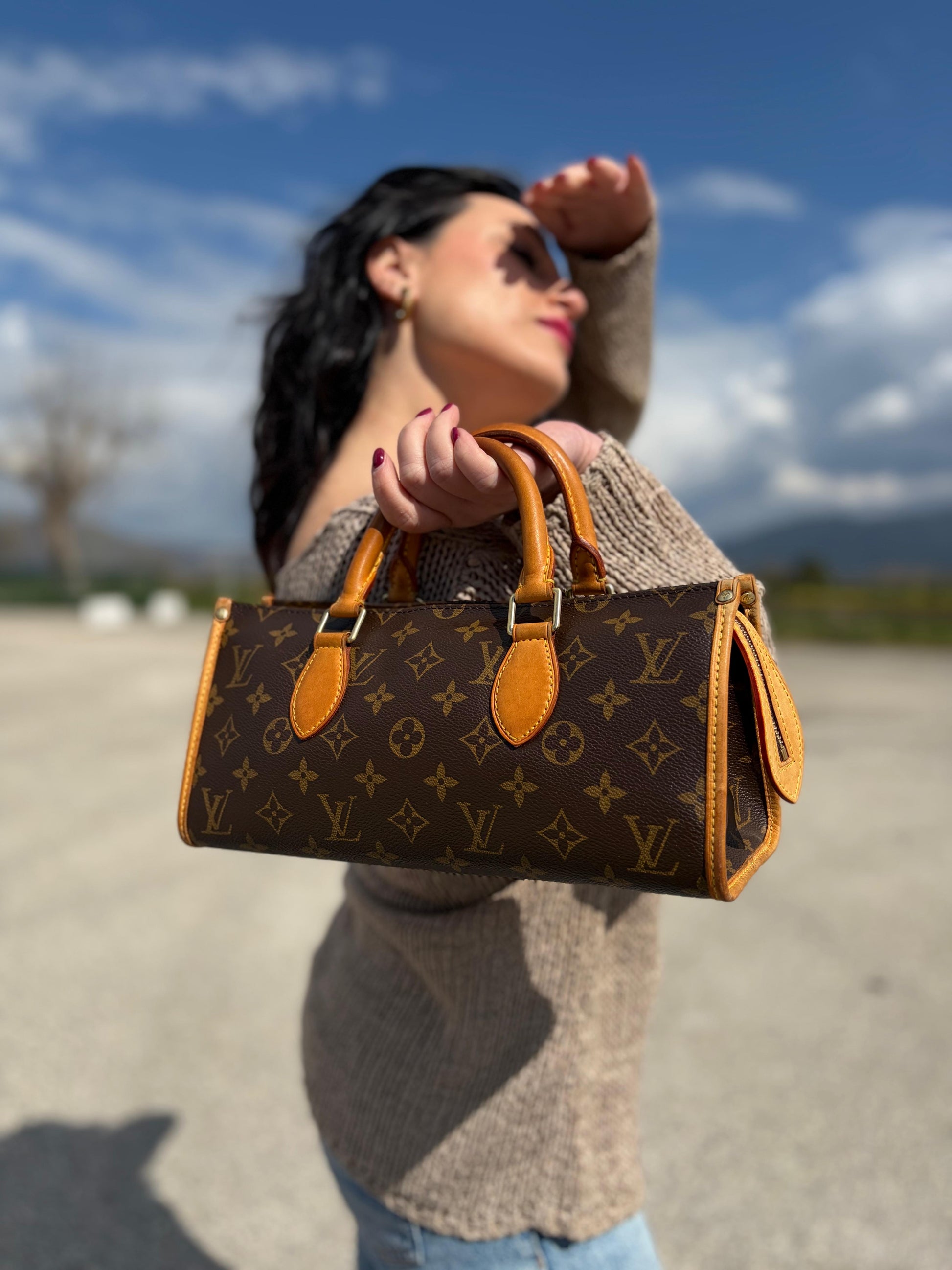 Ragazza che indossa una borsa LV Popincourt realizzata in tela Monogram con parti in vacchetta naturale, usata, originale, second hand, in ottime condizioni.