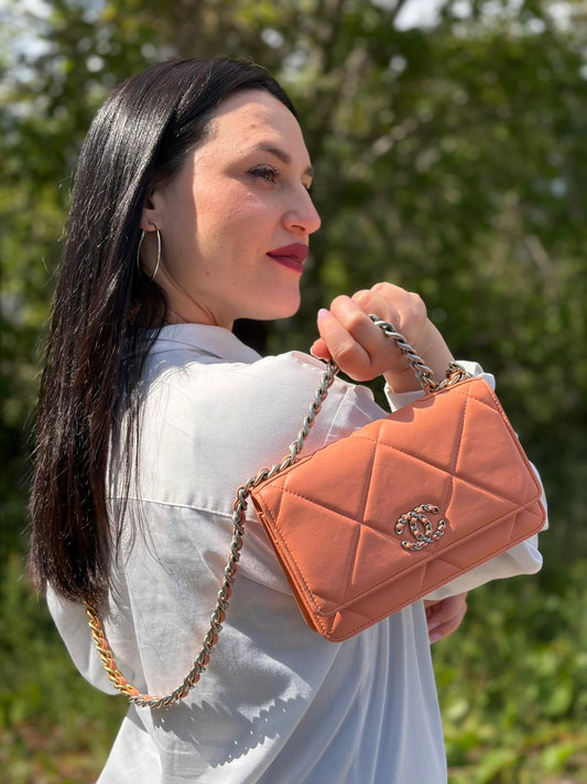 Ragazza che indossa un WOC Chanel in pelle trapuntata rosa albicocca e hardware bicolor, oro/argento, usata, originale, second hand, in ottime condizioni.