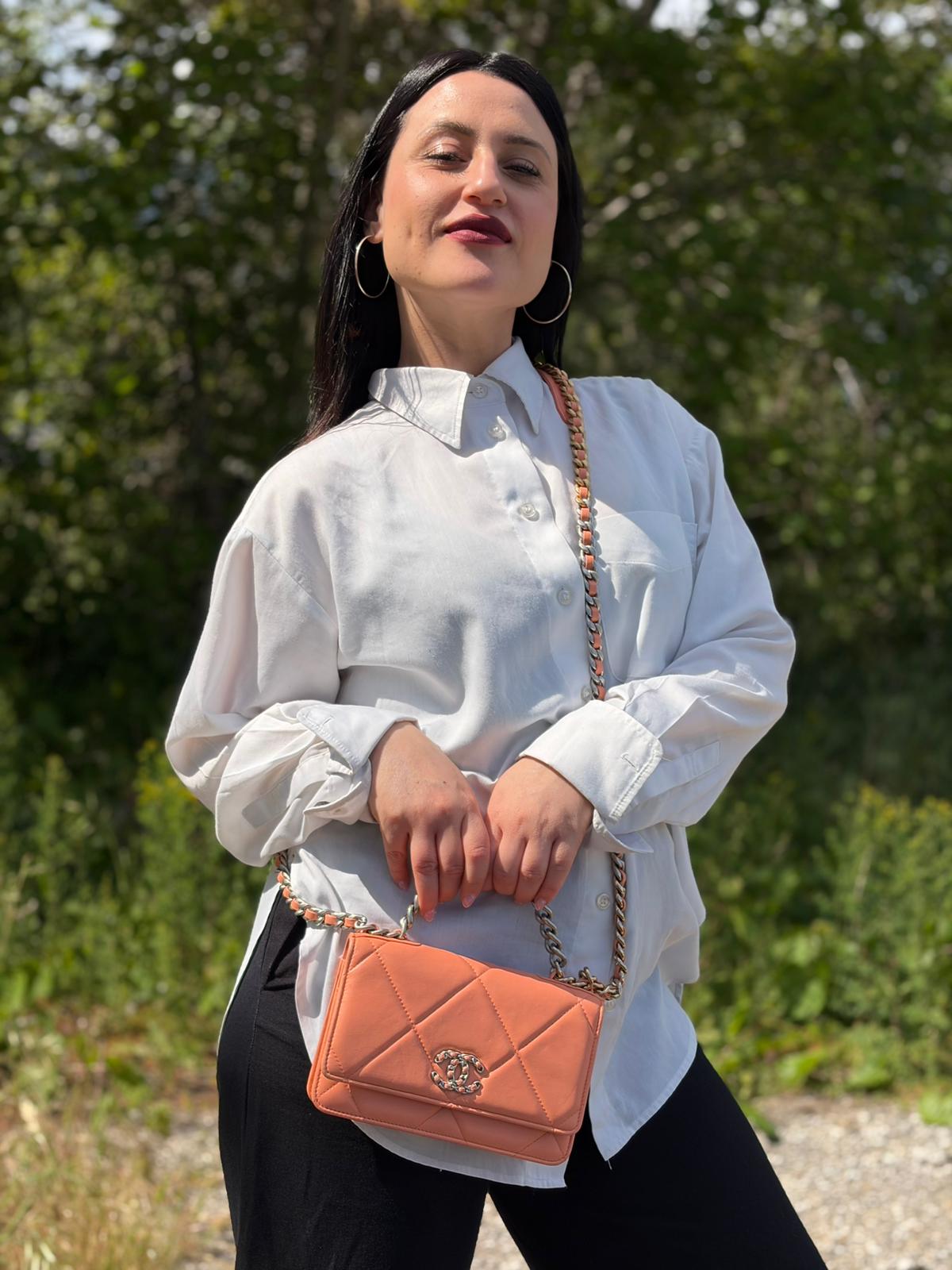 Ragazza che indossa un WOC Chanel in pelle trapuntata rosa albicocca e hardware bicolor, oro/argento, usata, originale, second hand, in ottime condizioni.