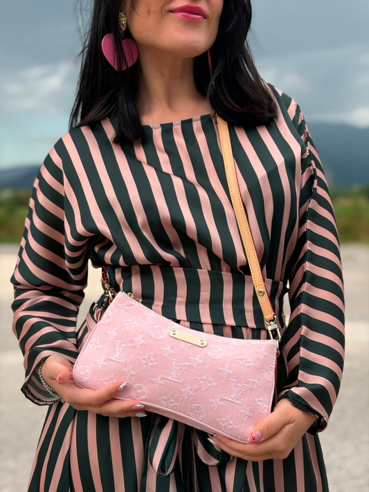 Ragazza che indossa una pochette Liv in denim rosa baby trama monogram, versatile e sicura, con doppia zip, catenella dorata e tracolla regolabile amovibili, usata, originale, second hand, in condizioni eccellenti.