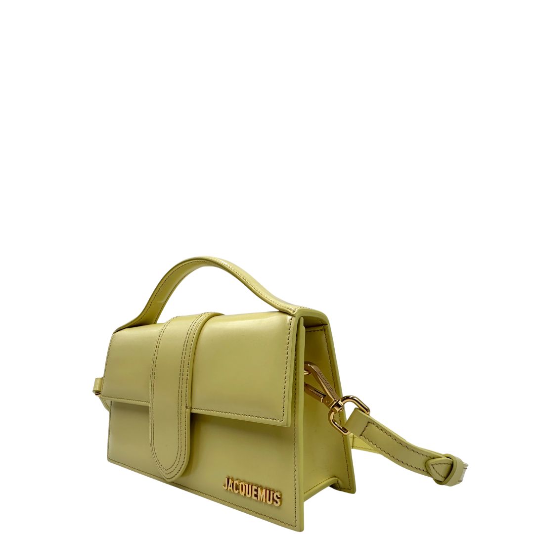 Laterali  Borsa Jacquemus in pelle glacé color giallo burro con parti metalliche dorate, munita di una tracolla regolabile e amovibile e un manico singolo