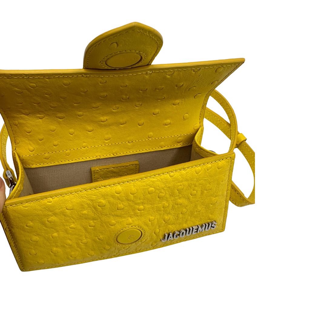Borsa Jacquemus in pelle gialla goffrata effetto struzzo, con parti metalliche argentate munita di un manico singolo e una tracolla regolabile e amovibile. 