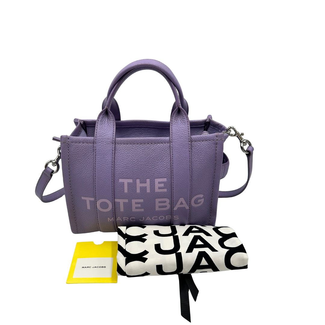 The Tote Bag Marc Jacobs in pelle lilla con parti metalliche argentate; munita di doppi manici e una tracolla amovibile e regolabile. Completa di dustbag, di lusso, originale, ottime condizioni. 