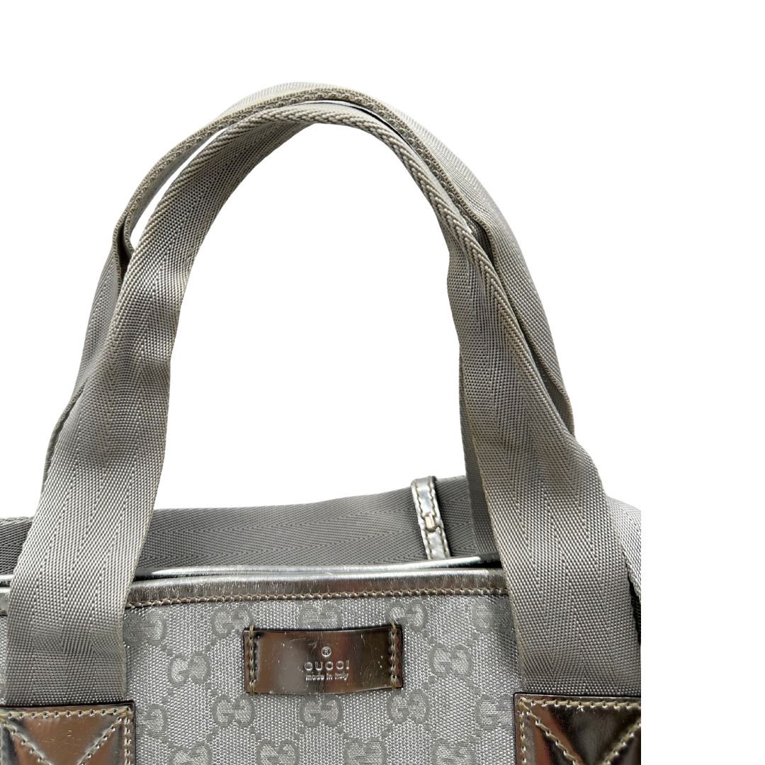 Manici Borsa Gucci in canvas grigio laminato GG con finiture in pelle Tono su tono e parti metalliche argentate. Dotata di Doppi manici e tracolla in tessuto regolabile.
