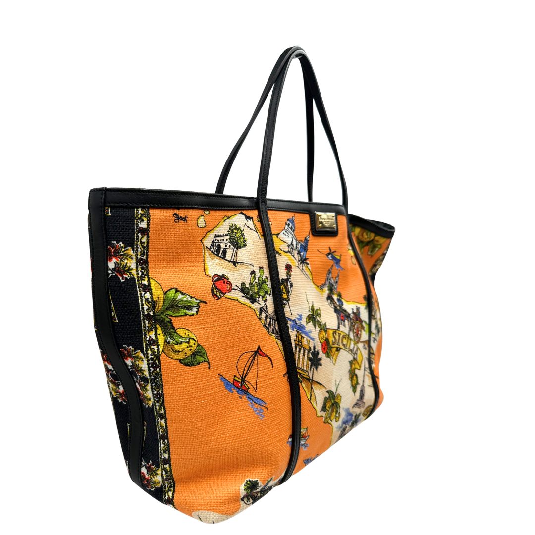 lato  Borsa Dolce & Gabbana in tessuto arancione con iconica grafica ispirata alla Sicilia, finiture in pelle nere e parti metalliche dorate; munita di doppi manici e una pochette estraibile. Completa di dustbag, originale, di lusso, ottime condizioni. 