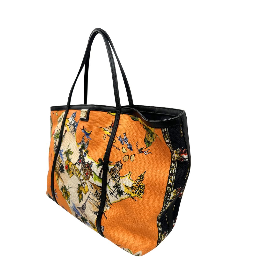 lato  Borsa Dolce & Gabbana in tessuto arancione con iconica grafica ispirata alla Sicilia, finiture in pelle nere e parti metalliche dorate; munita di doppi manici e una pochette estraibile. Completa di dustbag, originale, di lusso, ottime condizioni. 