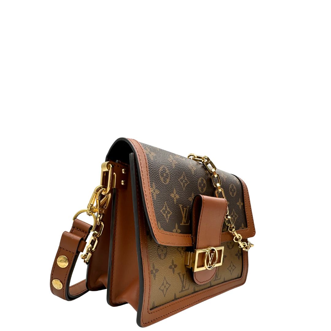 Laterali Borsa Dauphine MM Louis Vuitton in tela monogram, e monogram reverse bicolore con finiture in pelle cognac e parti metalliche dorate. Munita di una tracolla in pelle e un manico in catena, amovibili. Originale, usato, di lusso, in ottime condizioni 