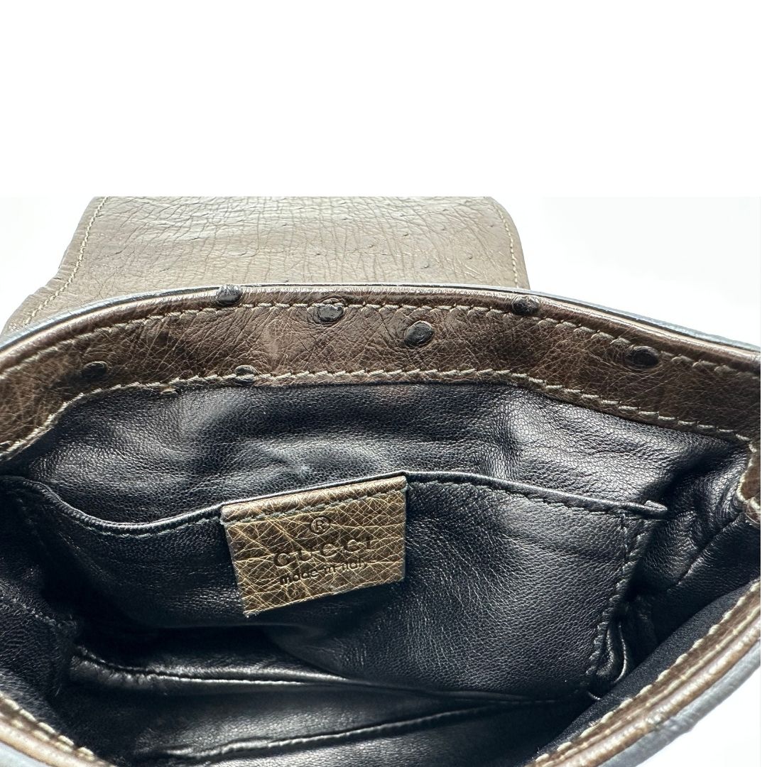 Interno di una borsa a tracolla Gucci 1973 in pelle marrone caffè trama struzzo con parti metalliche dorate. Munita di una tracolla in catena non amovibile e non regolabile. Completa di corredo.