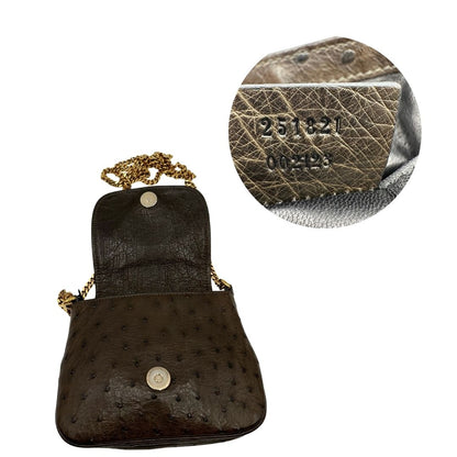 Apertura e codice di una borsa a tracolla Gucci 1973 in pelle marrone caffè trama struzzo con parti metalliche dorate. Munita di una tracolla in catena non amovibile e non regolabile. Completa di corredo.