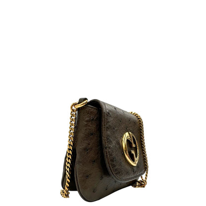 Laterale sinistro di una borsa a tracolla Gucci 1973 in pelle marrone caffè trama struzzo con parti metalliche dorate. Munita di una tracolla in catena non amovibile e non regolabile. Completa di corredo.