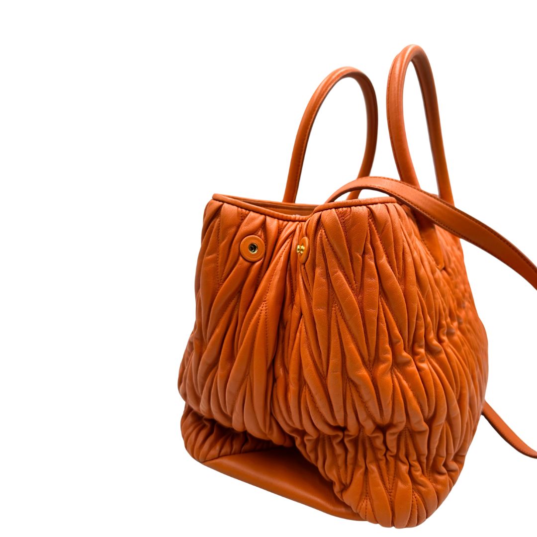 Angolo destro di una Borsa Miu Miu realizzata in nappa matelassé arancione con parti metalliche dorate; munita di due manici stondati e una tracolla regolabile amovibile. Originale, usata, di lusso, in ottime condizioni