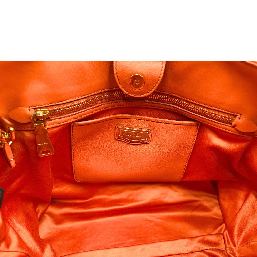Tasca di una Borsa Miu Miu realizzata in nappa matelassé arancione con parti metalliche dorate; munita di due manici stondati e una tracolla regolabile amovibile. Originale, usata, di lusso, in ottime condizioni