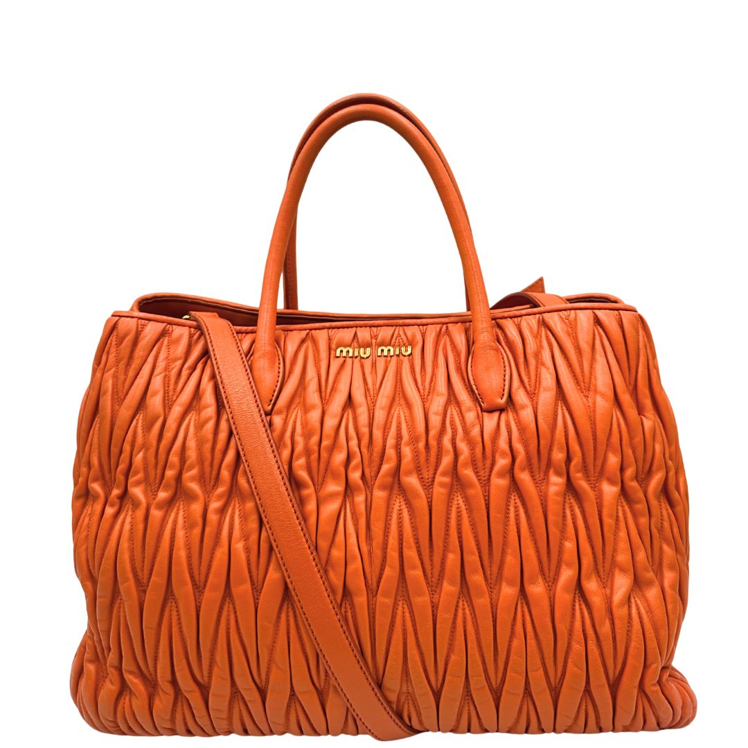 Front di una Borsa Miu Miu realizzata in nappa matelassé arancione con parti metalliche dorate; munita di due manici stondati e una tracolla regolabile amovibile. Originale, usata, di lusso, in ottime condizioni