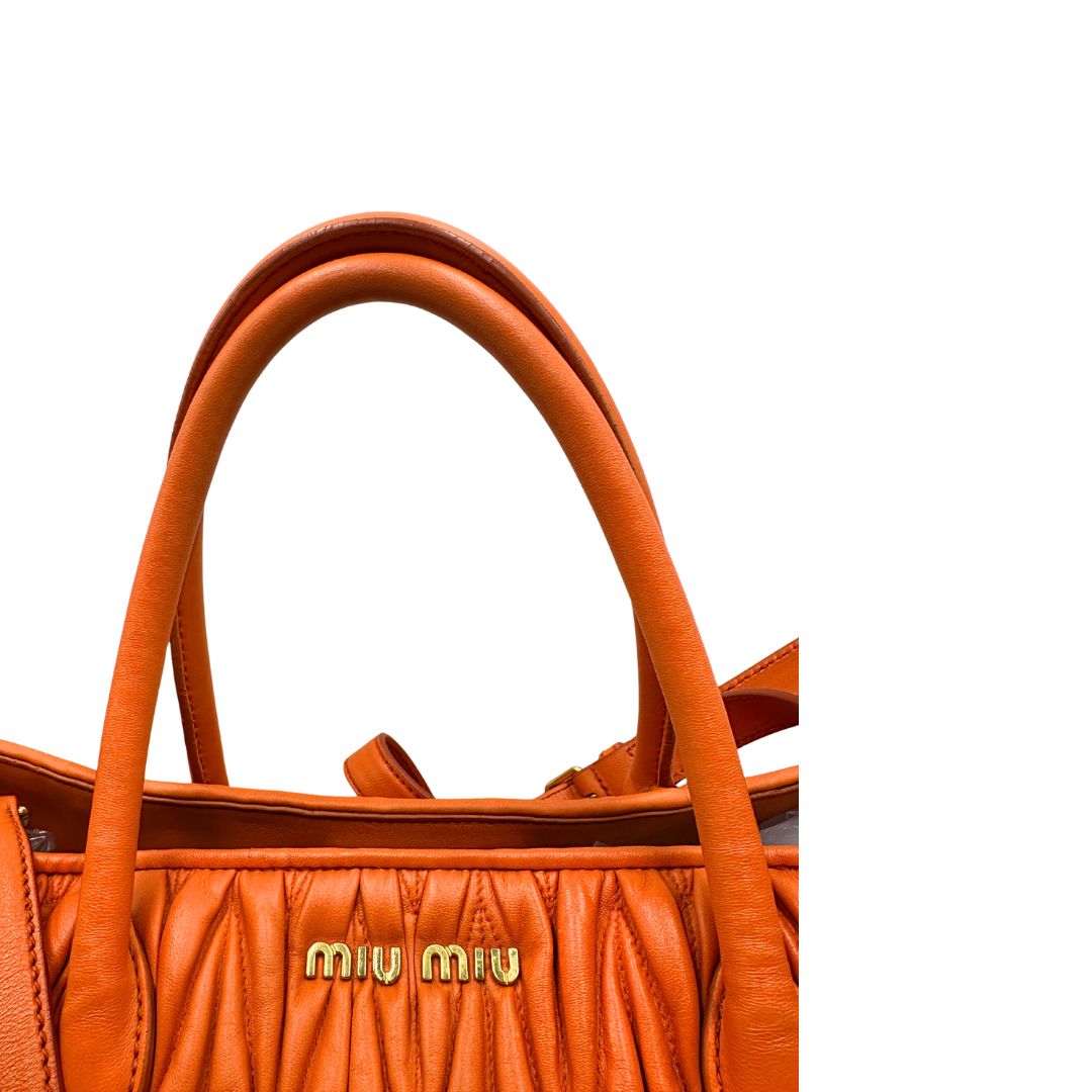 Manici di una Borsa Miu Miu realizzata in nappa matelassé arancione con parti metalliche dorate; munita di due manici stondati e una tracolla regolabile amovibile. Originale, usata, di lusso, in ottime condizioni