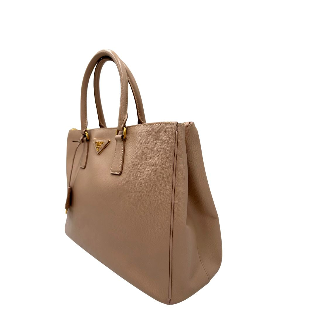 lato Borsa Prada in pelle saffiano rosa con parti metalliche dorate, munita di doppi manici stondati e una clochette portachiavi, di lusso, originale, usata.
