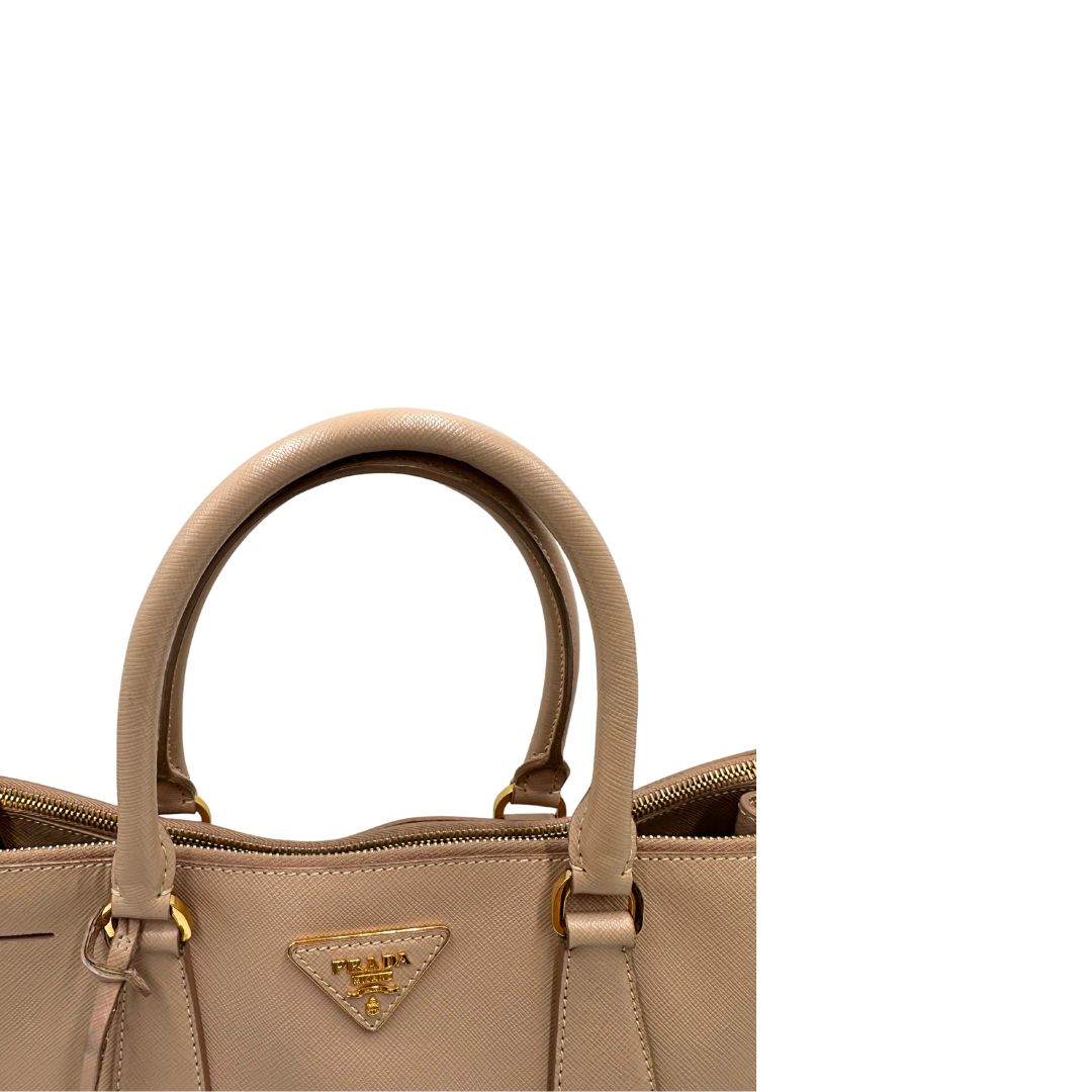 manici Borsa Prada in pelle saffiano rosa con parti metalliche dorate, munita di doppi manici stondati e una clochette portachiavi, di lusso, originale, usata.