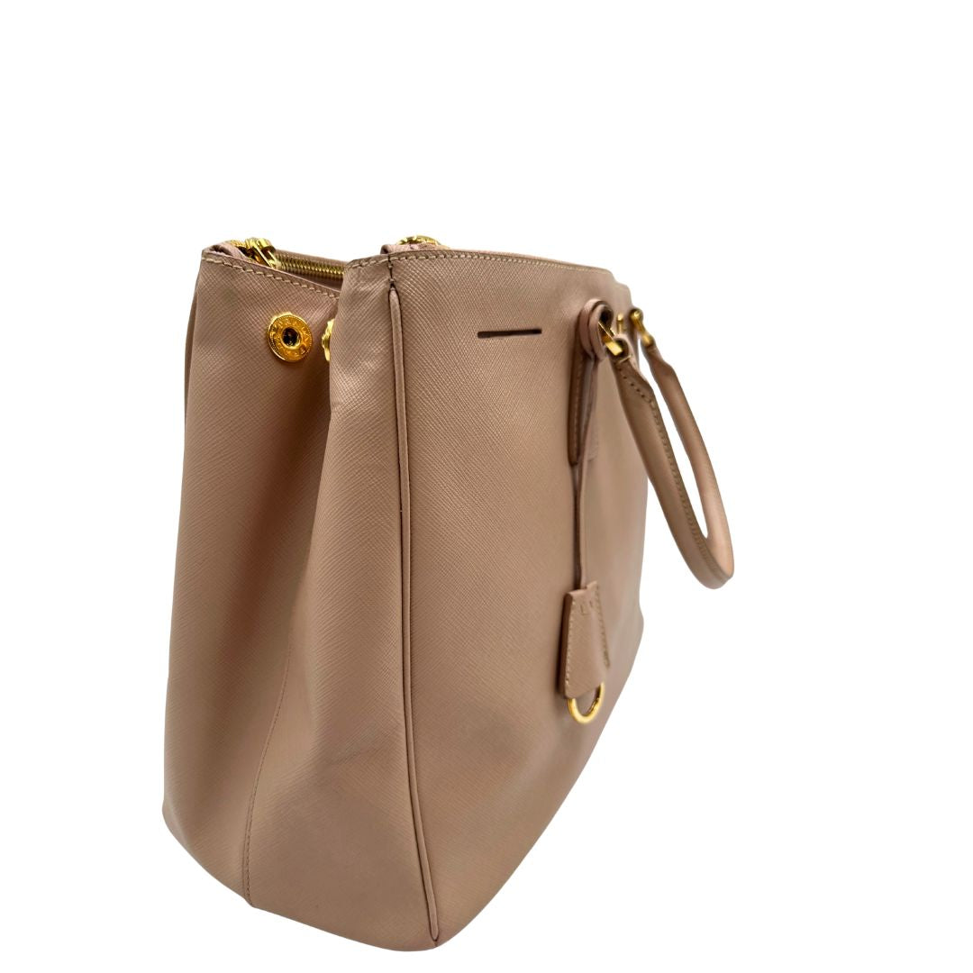 lato Borsa Prada in pelle saffiano rosa con parti metalliche dorate, munita di doppi manici stondati e una clochette portachiavi, di lusso, originale, usata. 