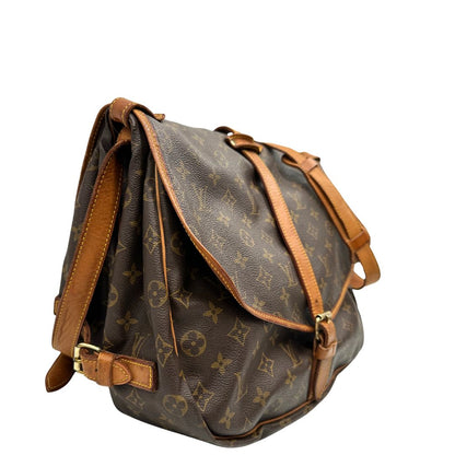 Lato destro di una Borsa Saumur 35 Louis Vuitton in canvas marrone monogram con finiture in vacchetta naturale e parti metalliche dorate; da indossare a tracolla. Originale, usata, di lusso, in ottime condizioni