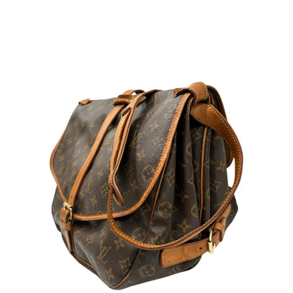 Lato sinistro di una Borsa Saumur 35 Louis Vuitton in canvas marrone monogram con finiture in vacchetta naturale e parti metalliche dorate; da indossare a tracolla. Originale, usata, di lusso, in ottime condizioni