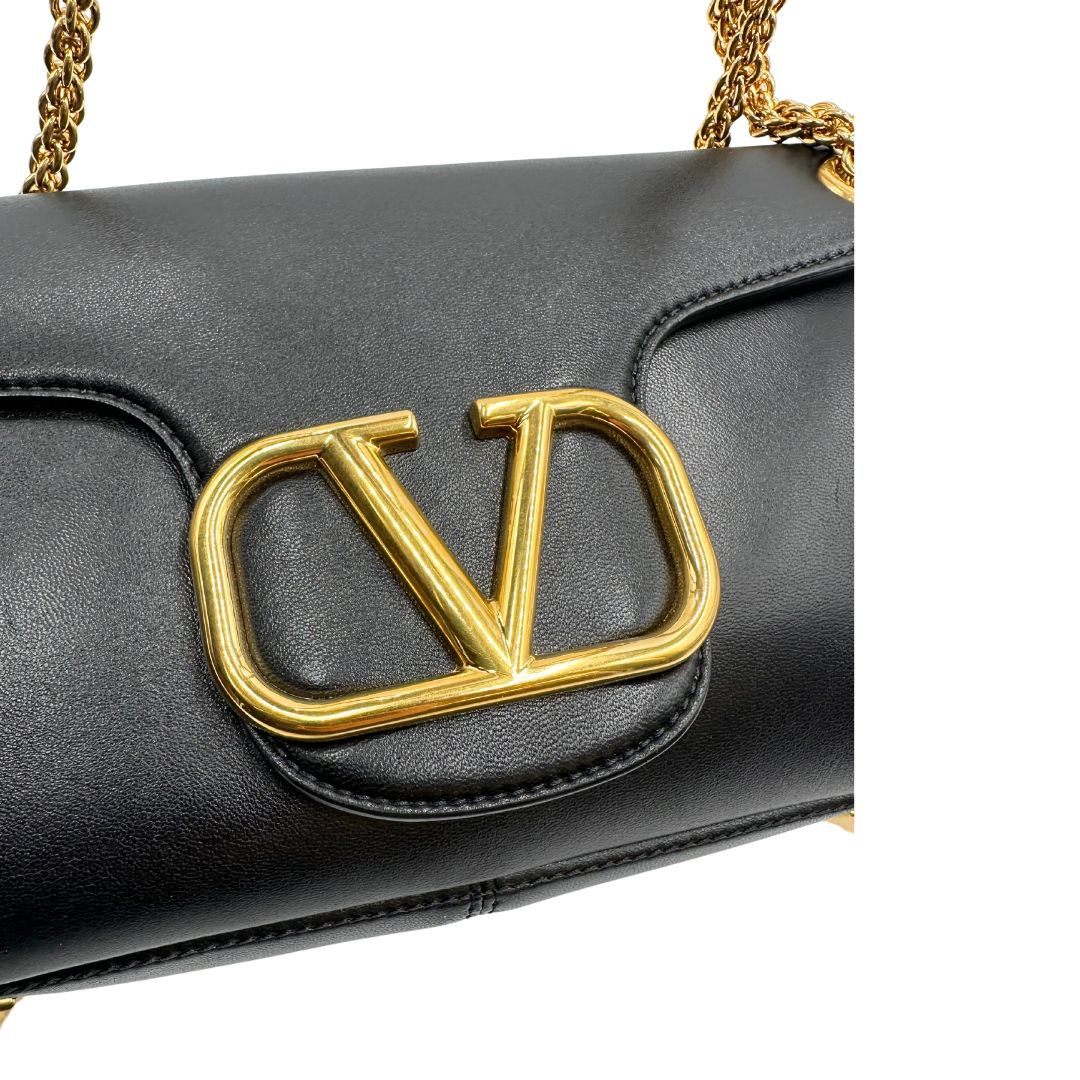 Chiusura di una Borsa Stud Sign Valentino Garavani in pelle nera con parti metalliche dorate e tracolla in catena scorrevole con borchie piramidali dorate sullo spallaccio. Completa di dustbag e cartellino. Originale, usata, di lusso, in ottime condizioni