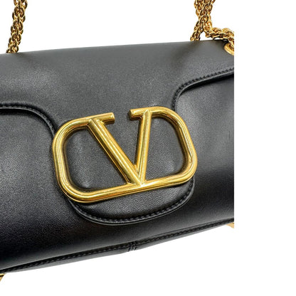 Chiusura di una Borsa Stud Sign Valentino Garavani in pelle nera con parti metalliche dorate e tracolla in catena scorrevole con borchie piramidali dorate sullo spallaccio. Completa di dustbag e cartellino. Originale, usata, di lusso, in ottime condizioni